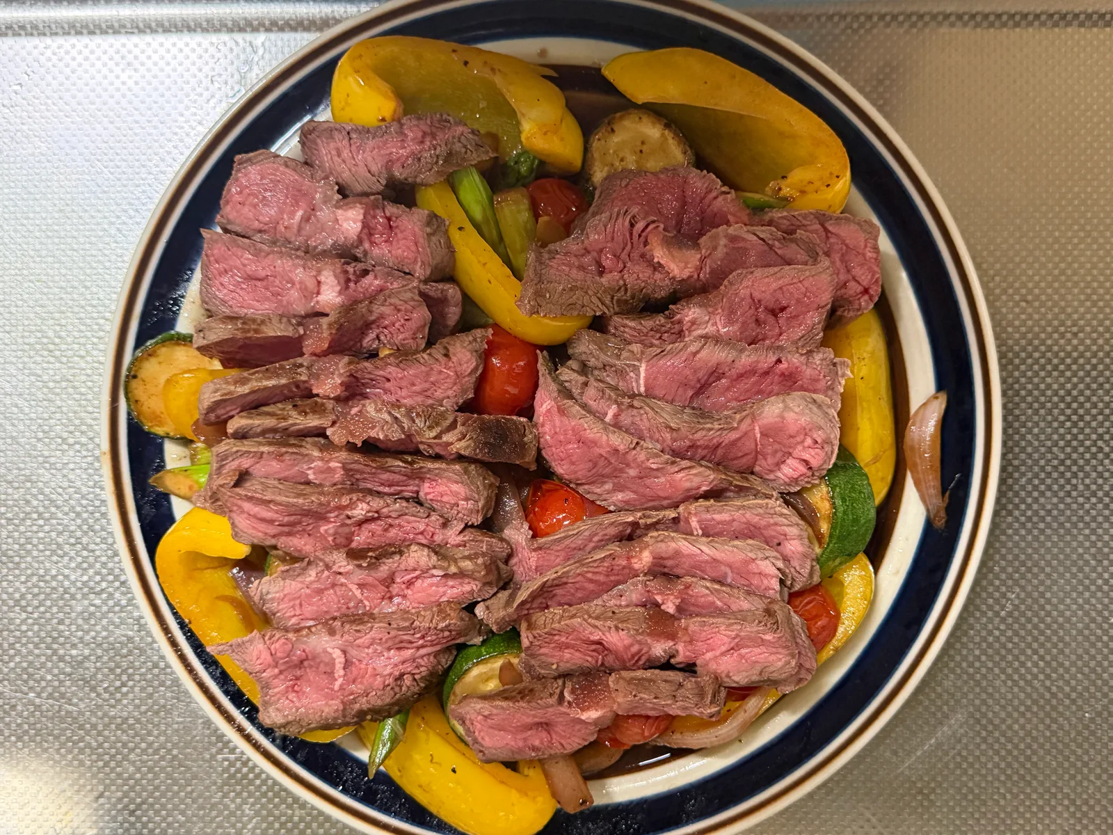 焼いて薄切りにしたミスジのステーキを、焼き野菜の上に盛り付けた一皿