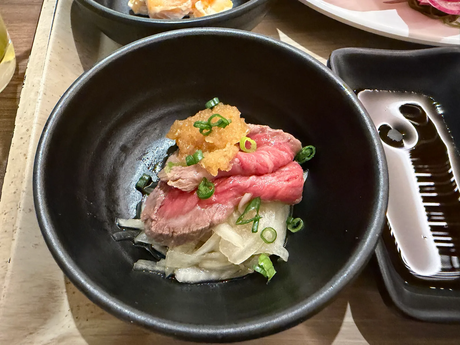 黒い小鉢のローストビーフ。おろしとねぎがのっている