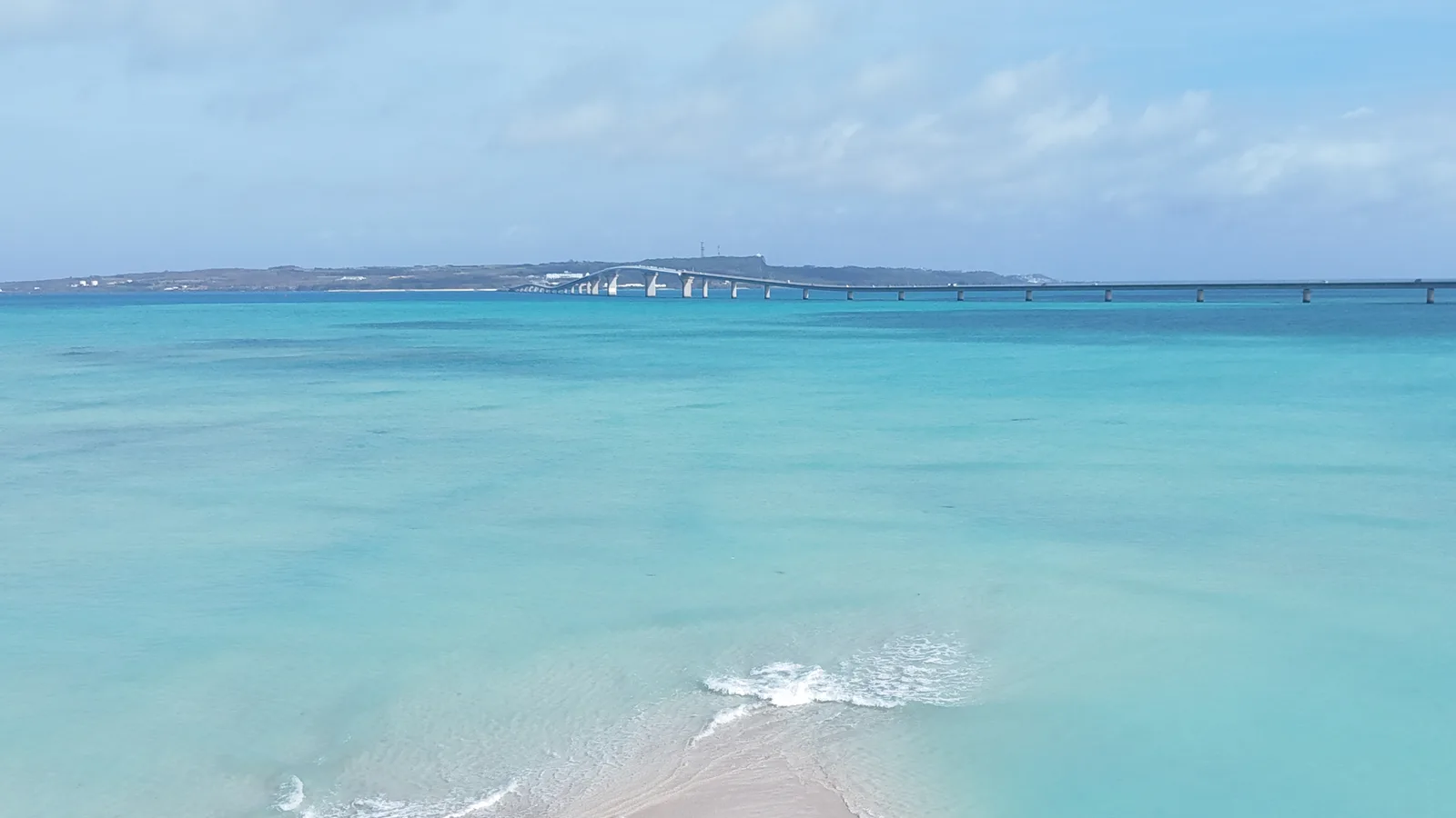 遠くに長い橋が見えるユニの浜の海